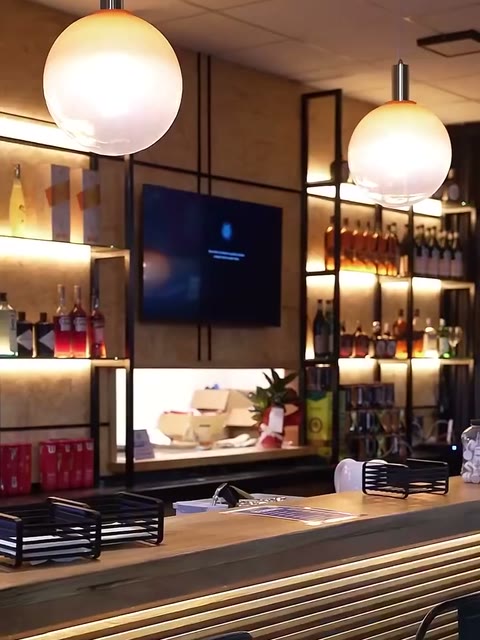 La barra de madera de Box con lámparas redondas y botellas iluminadas.